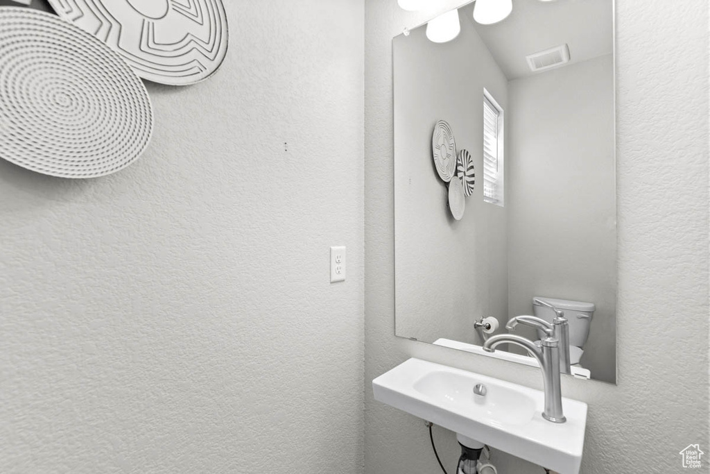 Bathroom featuring a sink, a textured wall, and visible vents