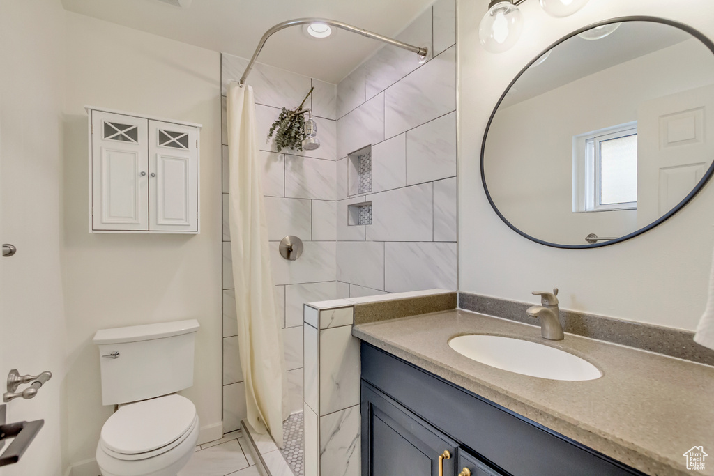 Bathroom with tile patterned floors, a shower with shower curtain, toilet, and vanity