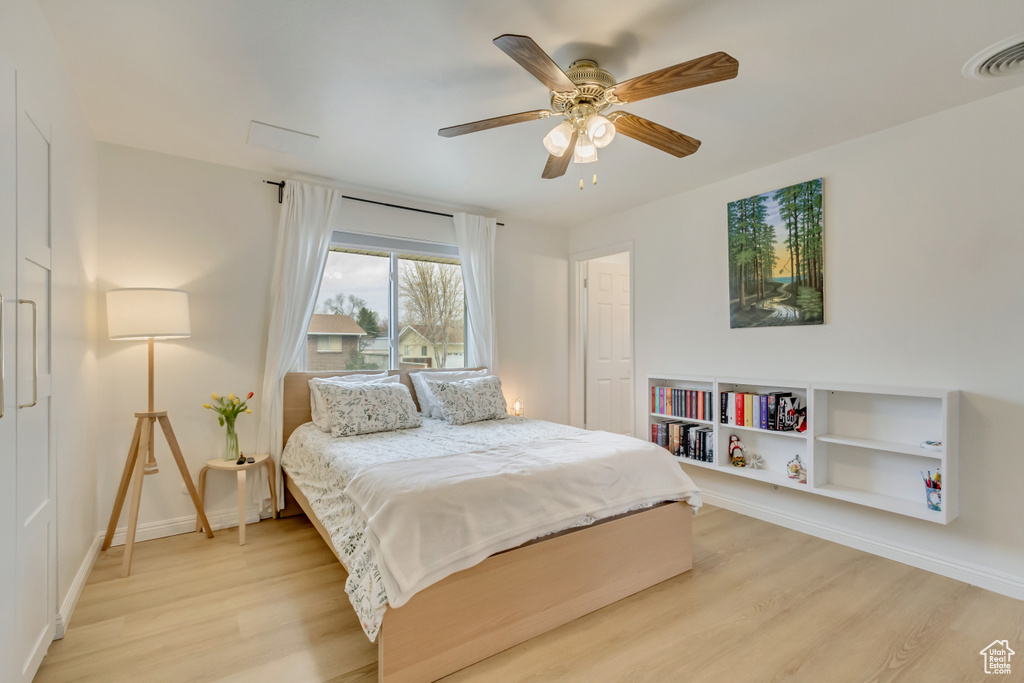 Bedroom with a ceiling fan, baseboards, light wood-style floors, and visible vents