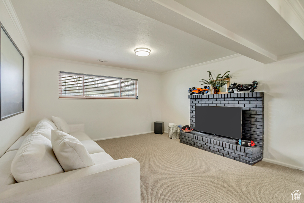 Living room featuring baseboards, crown molding, carpet, and a brick fireplace