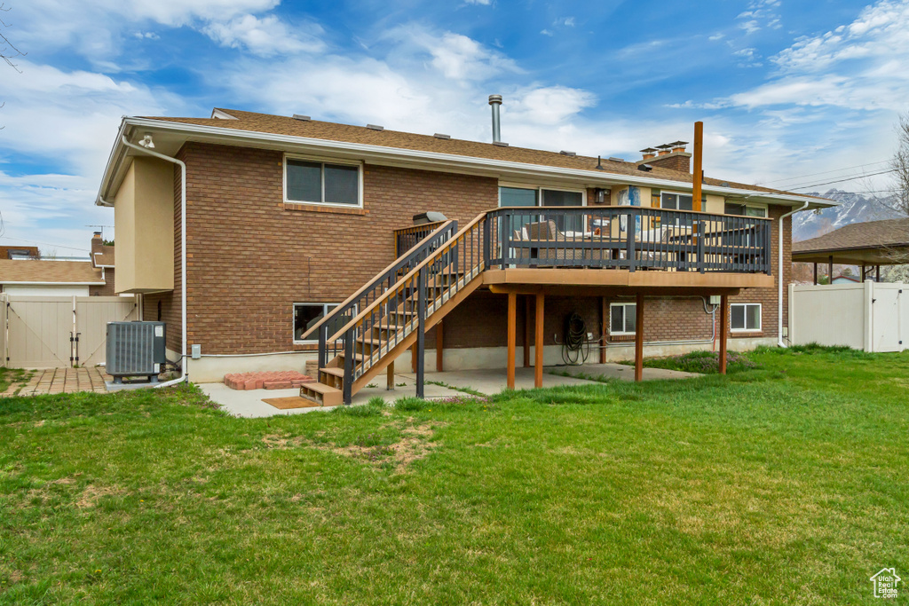 Back of house featuring brick siding, a gate, central AC unit, and a yard