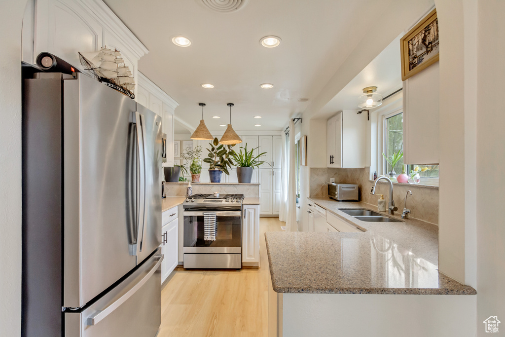 Kitchen with white cabinets, a sink, a peninsula, and appliances with stainless steel finishes