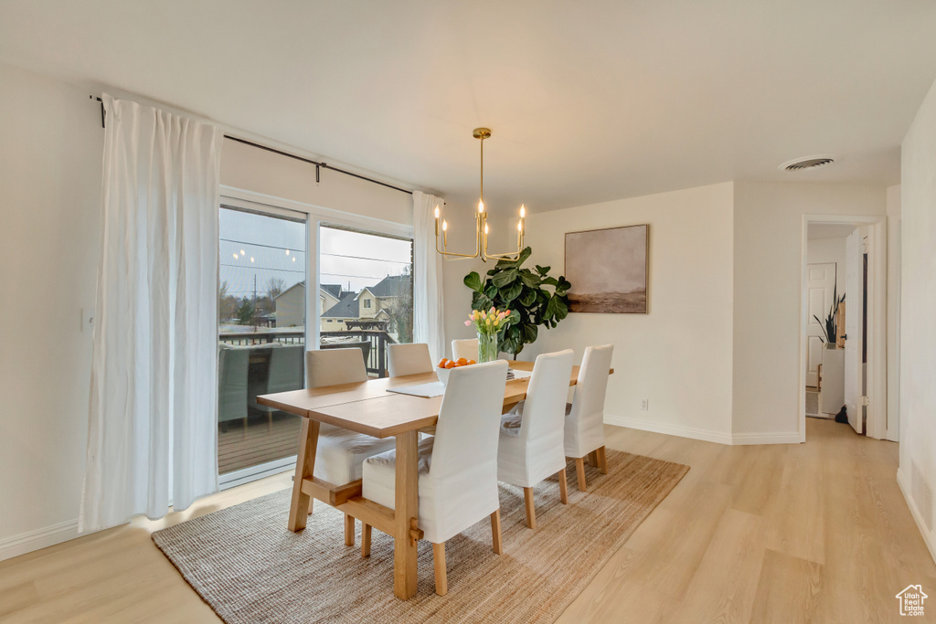 Dining area with light wood finished floors, baseboards, a chandelier, and visible vents