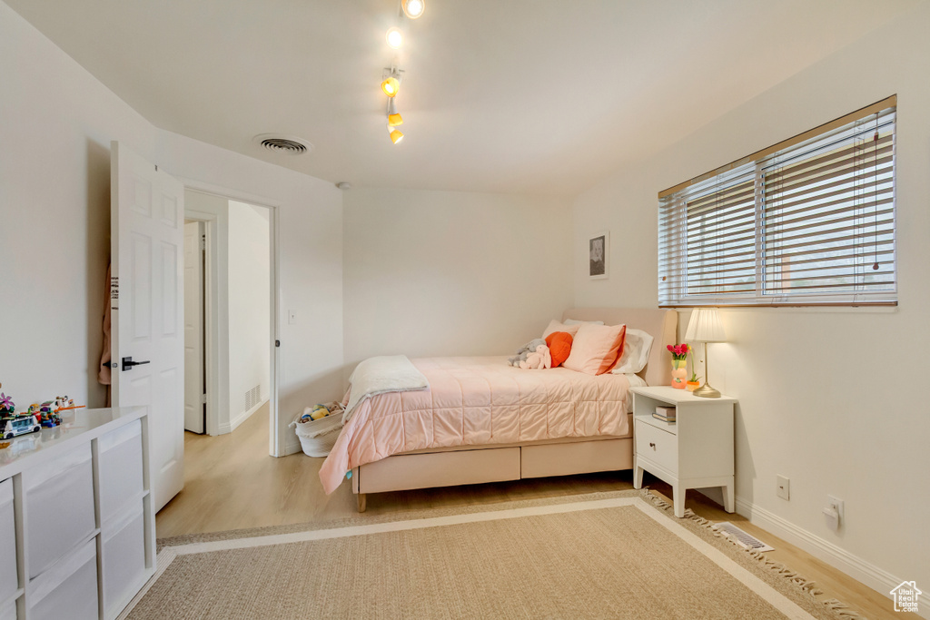Bedroom with baseboards, visible vents, and wood finished floors