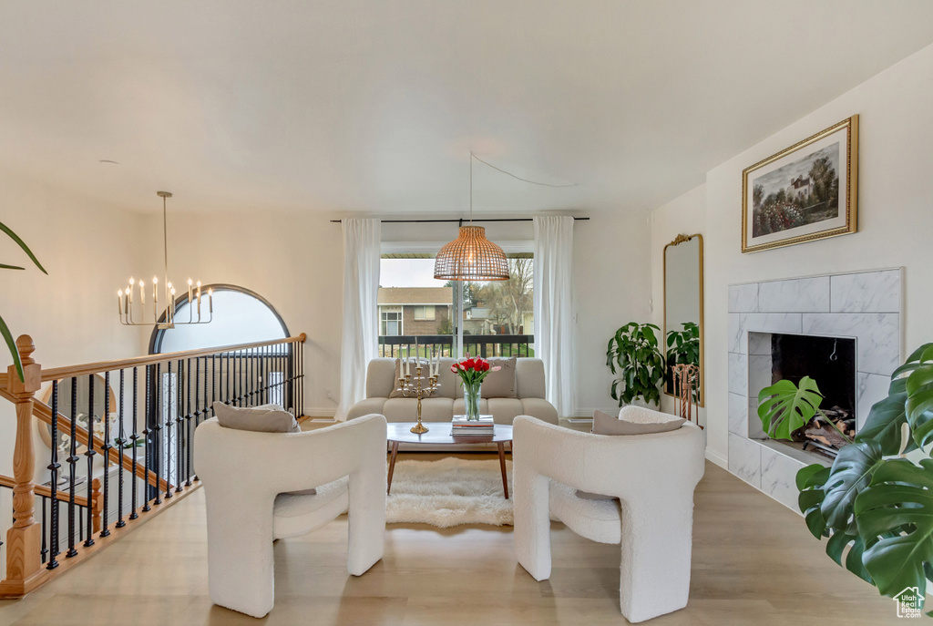 Living room featuring a tiled fireplace, light wood finished floors, and a chandelier