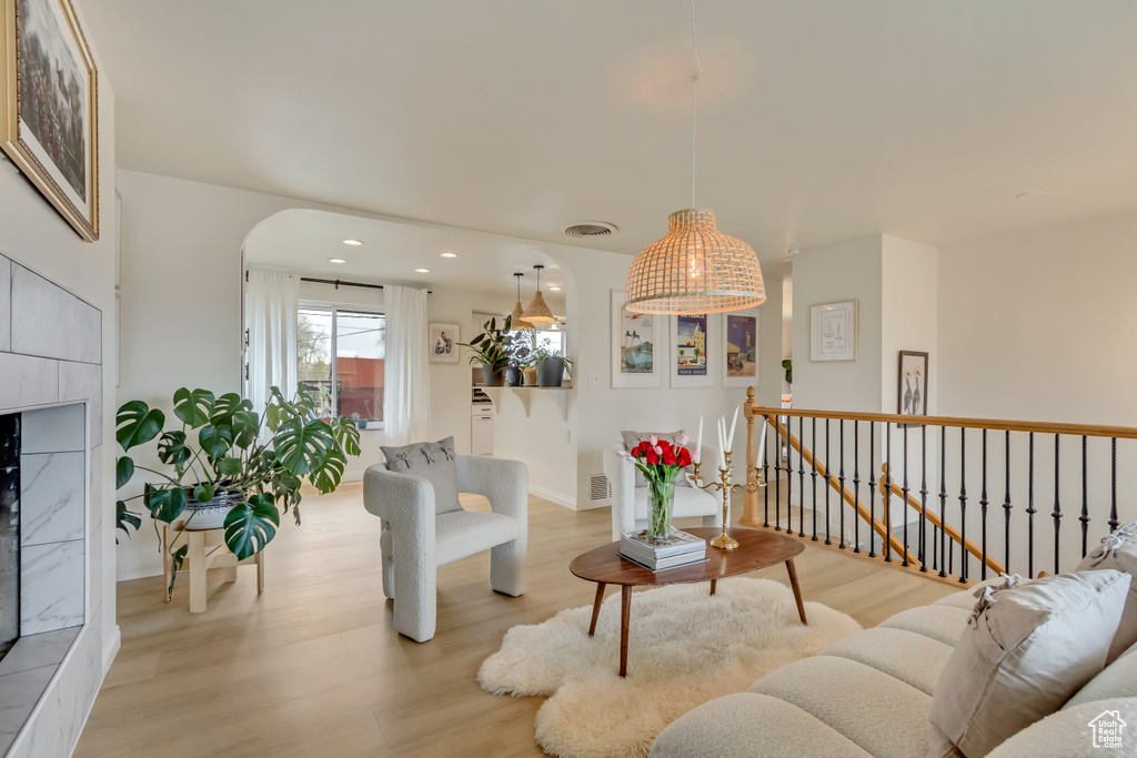 Living room featuring light wood-type flooring, baseboards, visible vents, arched walkways, and recessed lighting