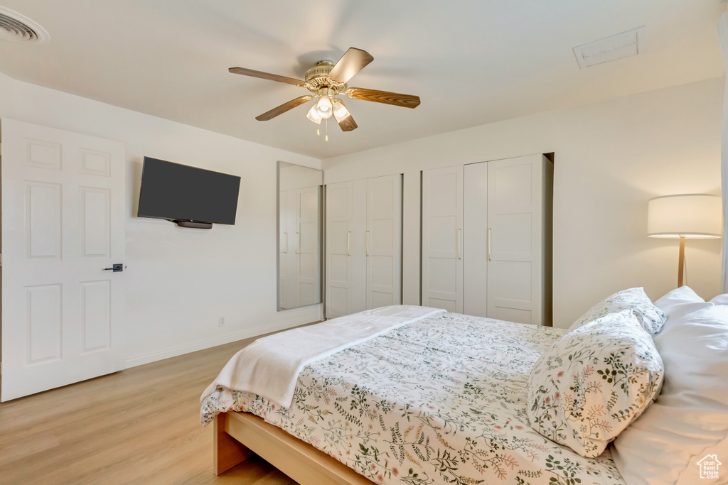 Bedroom featuring a ceiling fan, light wood-type flooring, baseboards, visible vents, and two closets