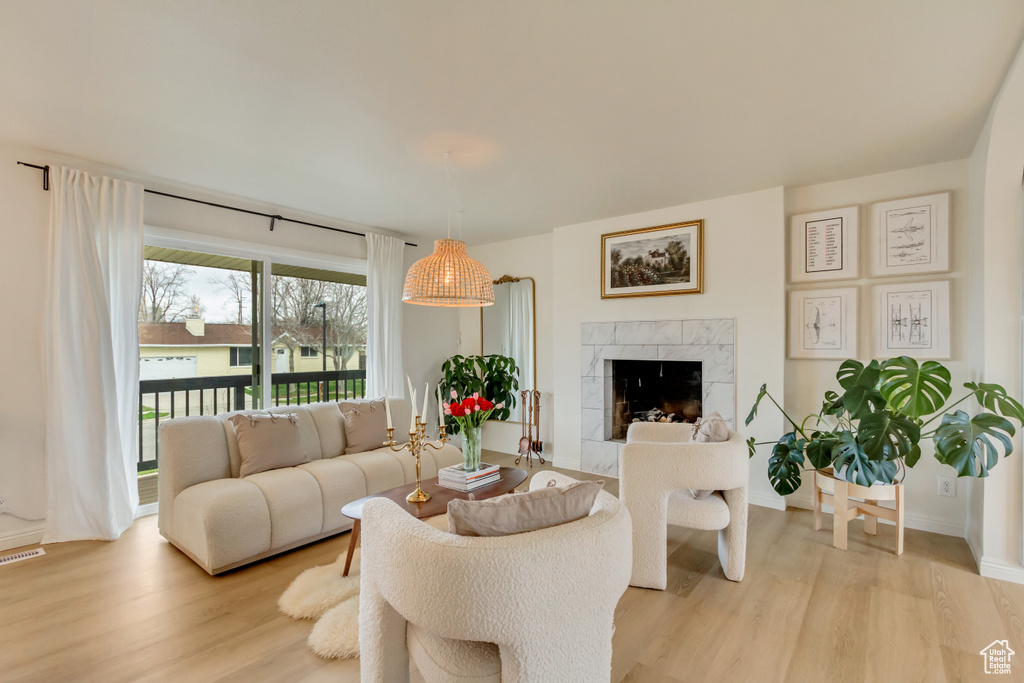 Living room with baseboards, a tile fireplace, and light wood finished floors