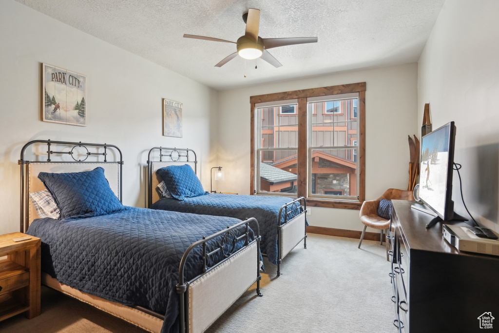 Bedroom with light carpet, baseboards, ceiling fan, and a textured ceiling