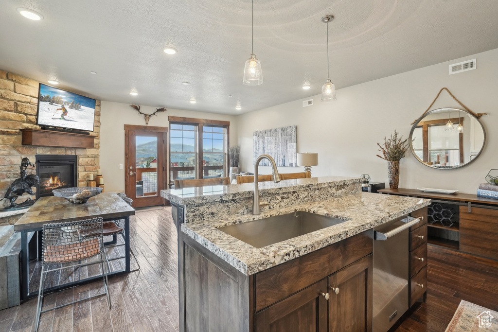 Kitchen with open floor plan, dark wood-style flooring, a sink, visible vents, and dishwasher