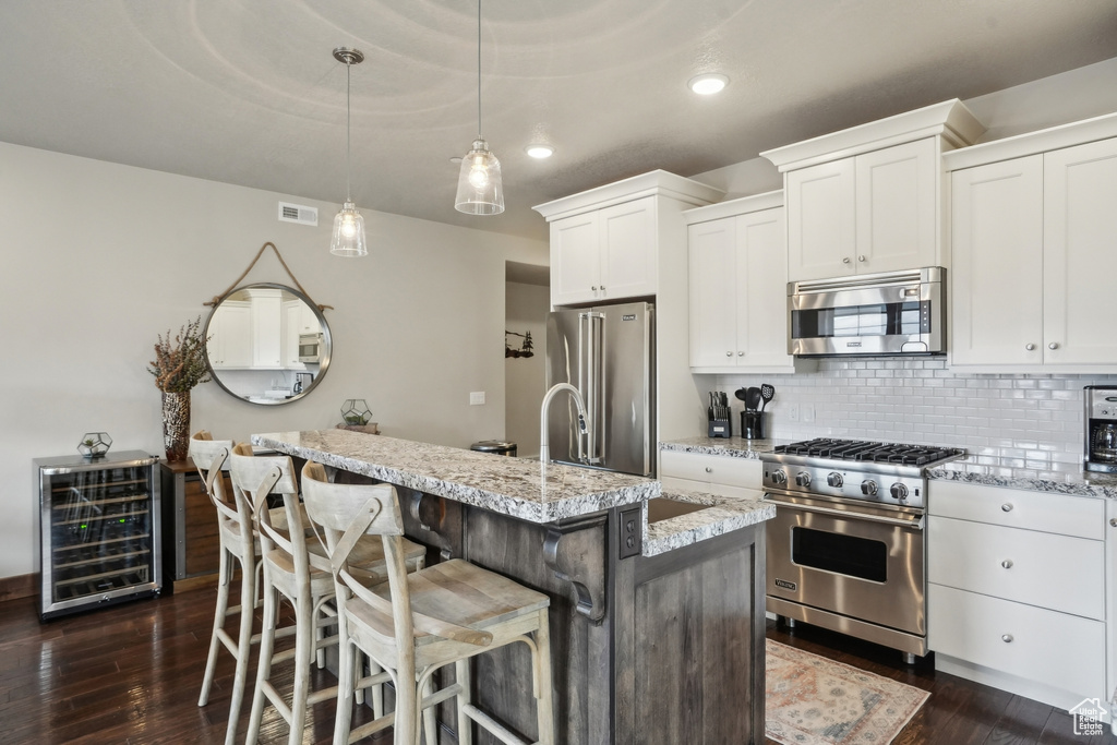 Kitchen featuring backsplash, beverage cooler, high quality appliances, dark wood-style floors, and visible vents