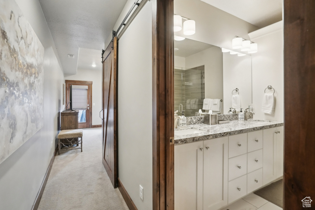 Full bathroom with double vanity, a sink, a shower with door, and baseboards