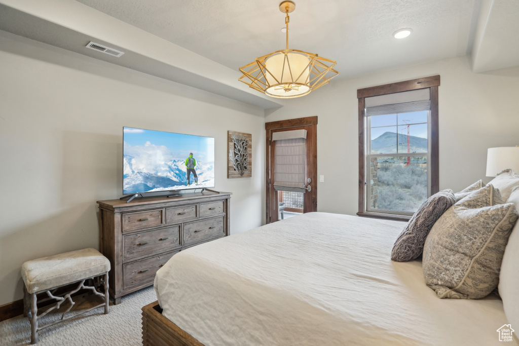 Carpeted bedroom featuring visible vents and a chandelier