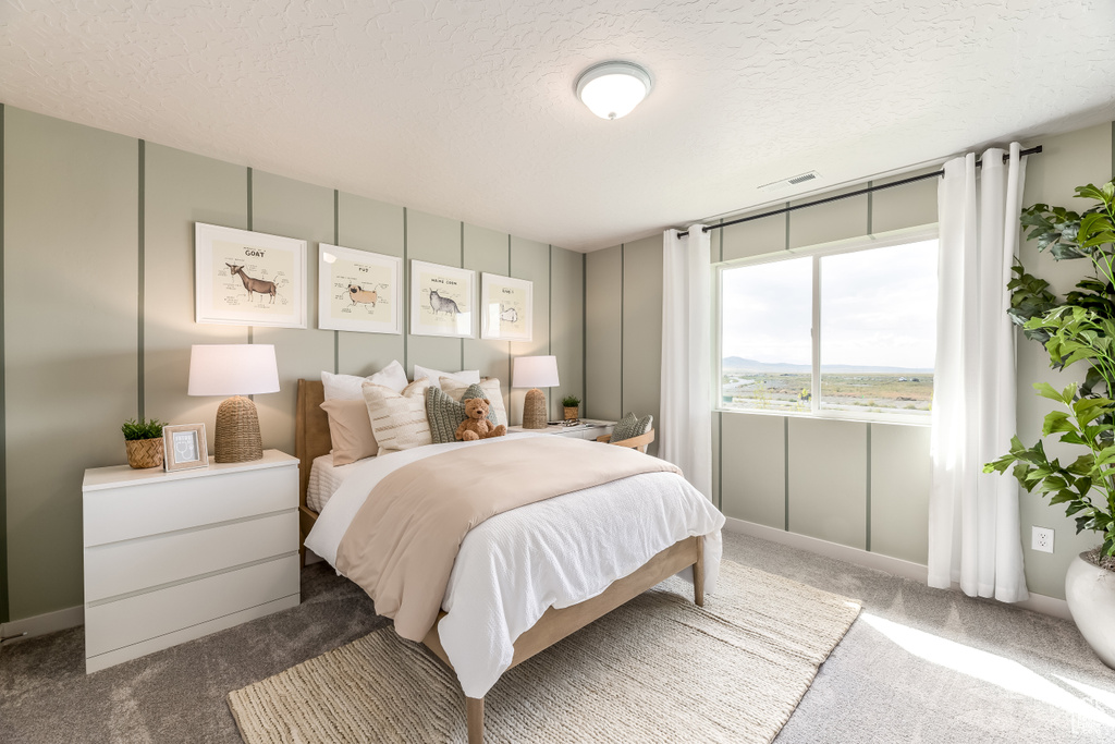 Carpeted bedroom with a textured ceiling and visible vents