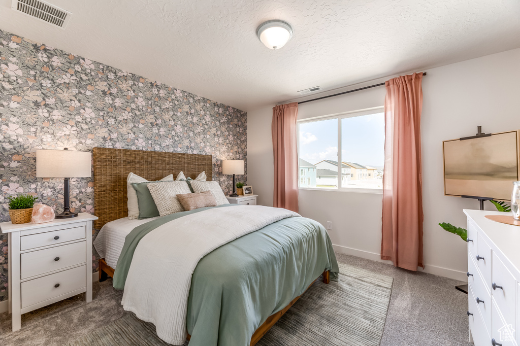 Bedroom with baseboards, visible vents, wallpapered walls, and a textured ceiling