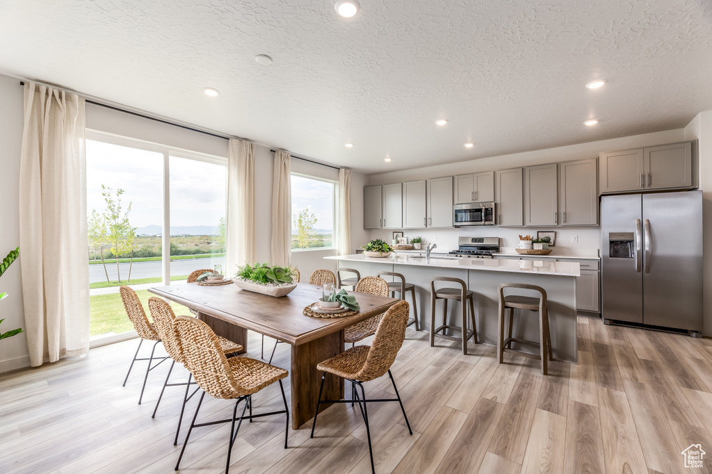 Dining space with a textured ceiling, recessed lighting, and light wood finished floors