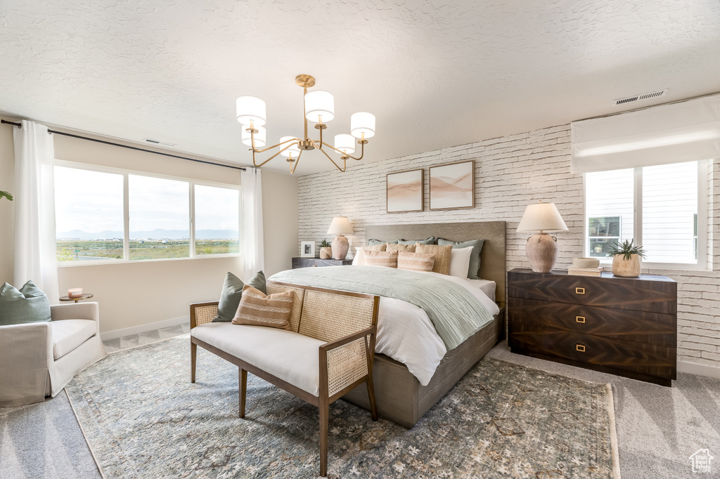Bedroom with a textured ceiling, visible vents, multiple windows, and a notable chandelier