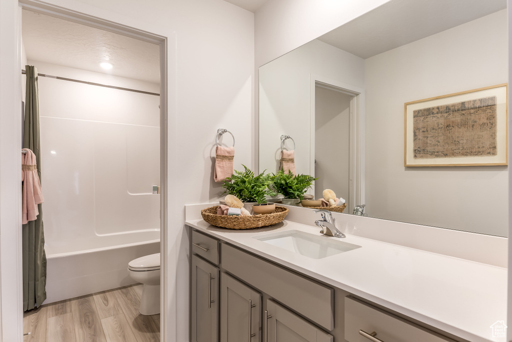 Full bathroom featuring shower / bath combination with curtain, toilet, vanity, and wood finished floors