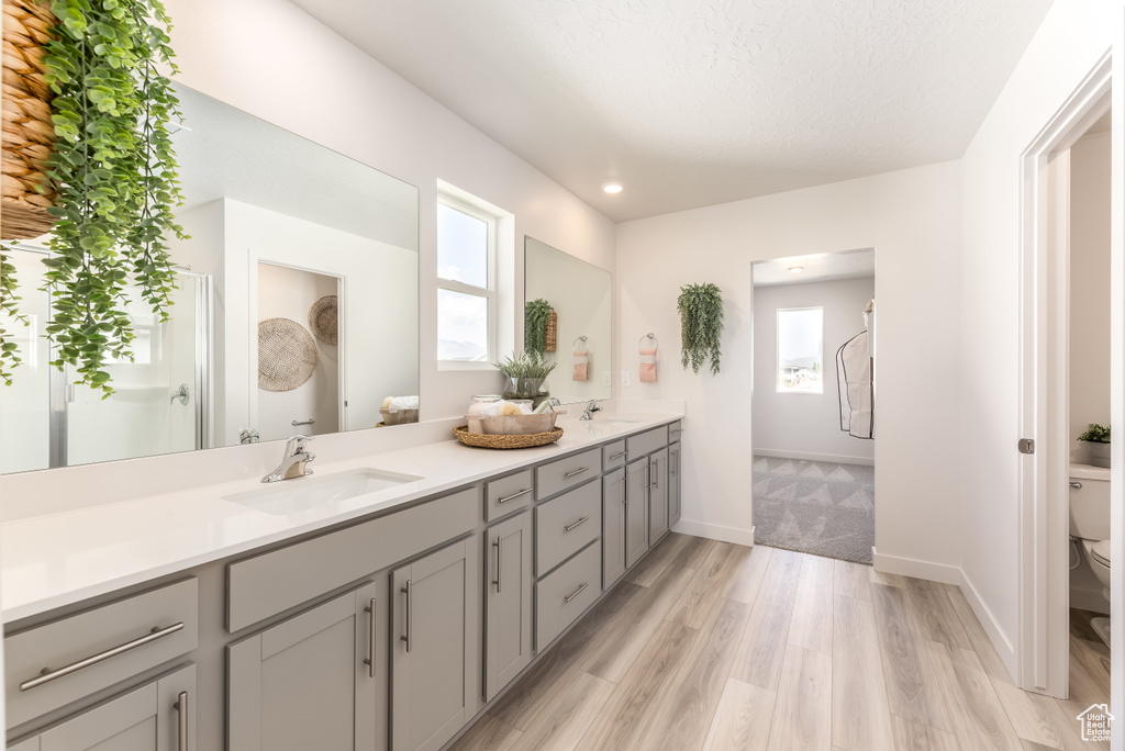 Bathroom with a sink, double vanity, toilet, and wood finished floors