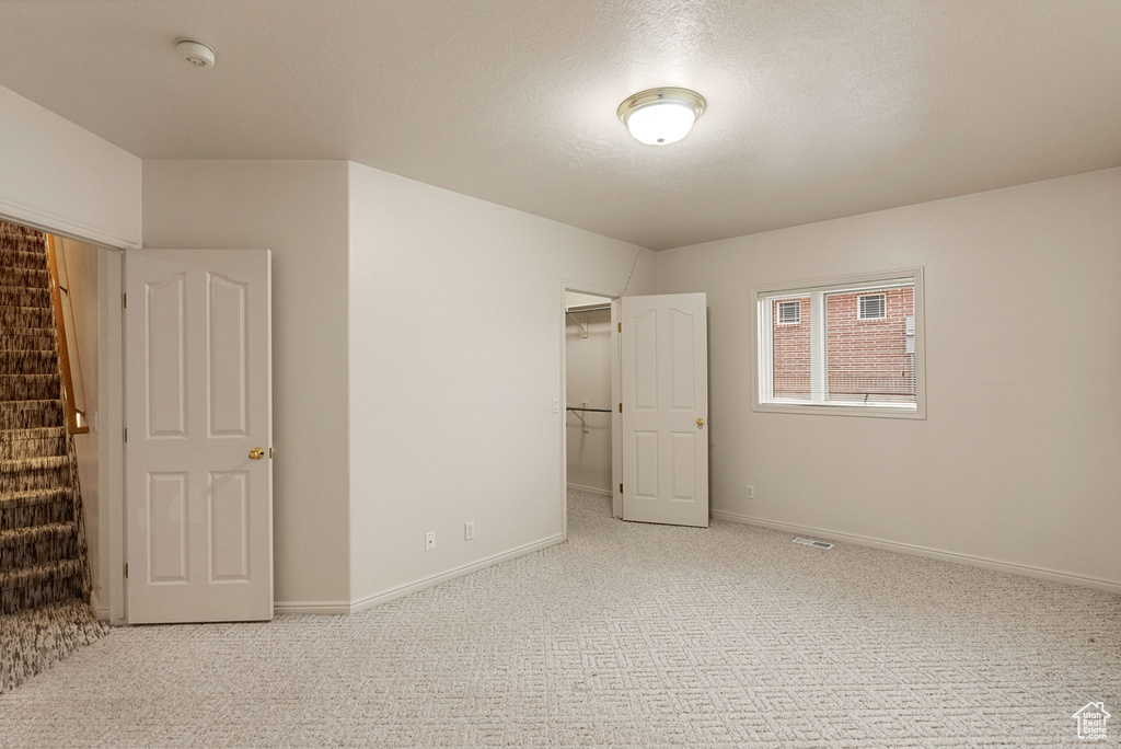 Unfurnished bedroom featuring a closet, a spacious closet, baseboards, visible vents, and carpet