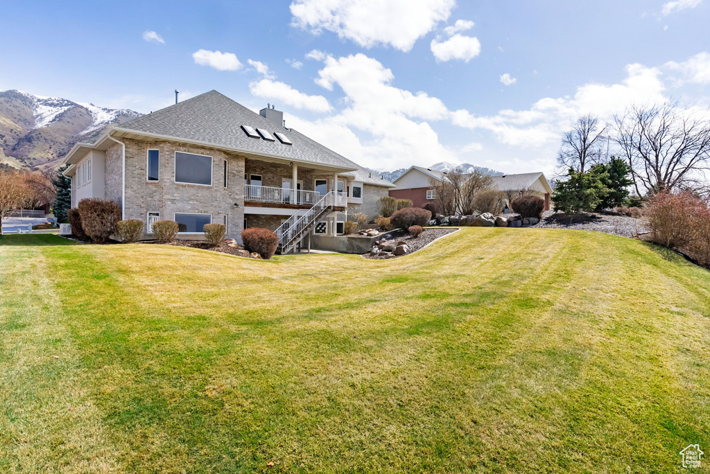 Rear view of property featuring brick siding, a mountain view, stairway, and a yard
