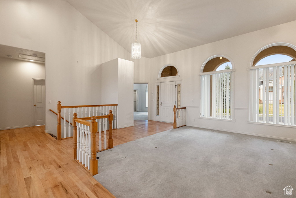 Carpeted empty room with baseboards, a high ceiling, and wood finished floors