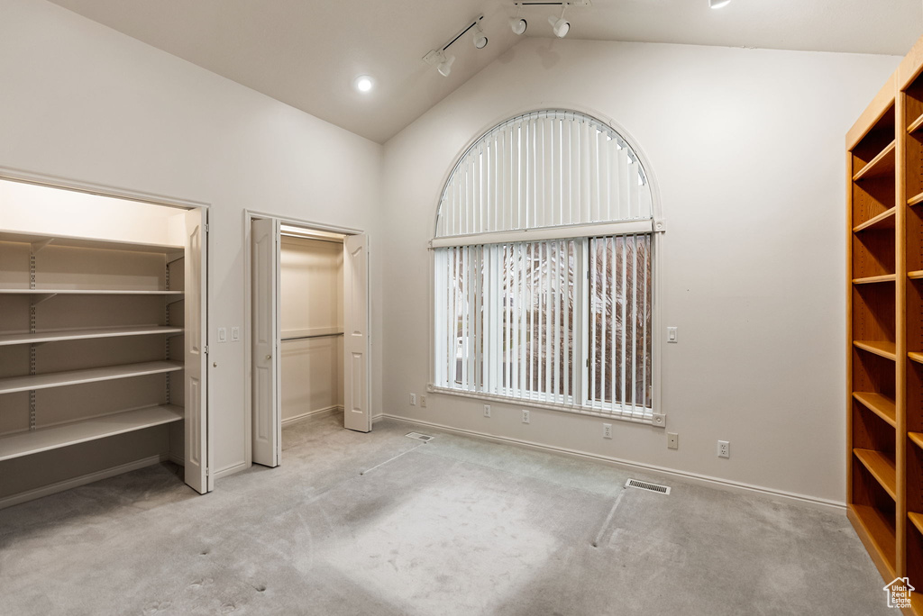 Unfurnished bedroom featuring two closets, carpet flooring, lofted ceiling, and visible vents