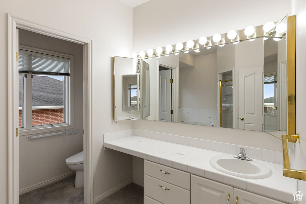 Bathroom featuring toilet, vanity, a shower with shower door, and baseboards
