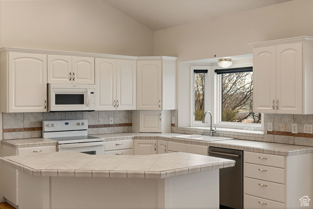 Kitchen featuring white appliances, white cabinetry, and a sink