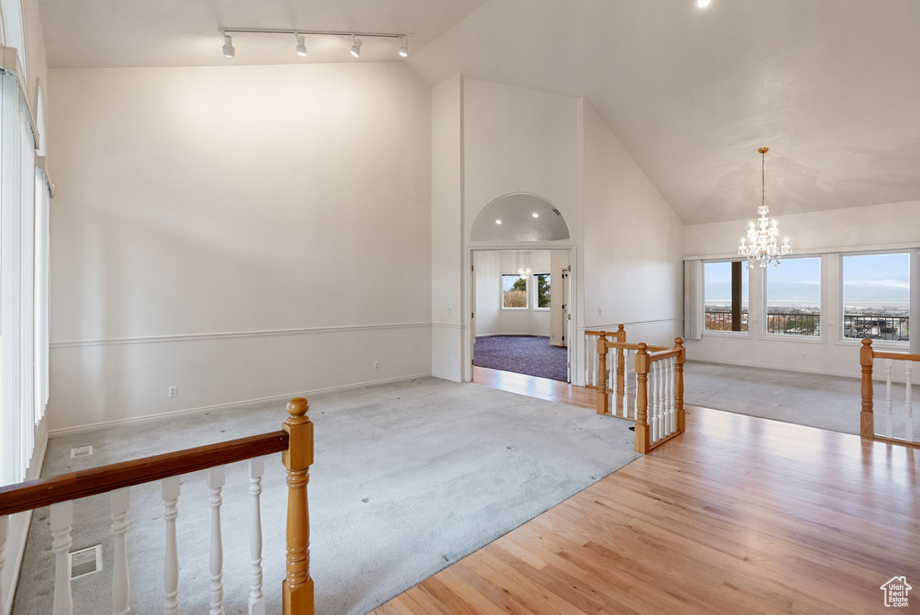Interior space featuring a notable chandelier, high vaulted ceiling, wood finished floors, baseboards, and track lighting