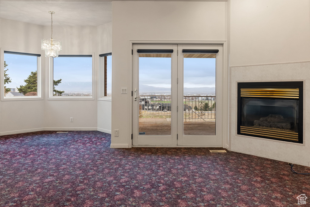 Interior space with baseboards, a notable chandelier, carpet flooring, and a glass covered fireplace