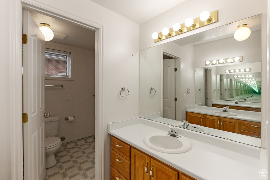 Bathroom with toilet, tile patterned floors, and vanity