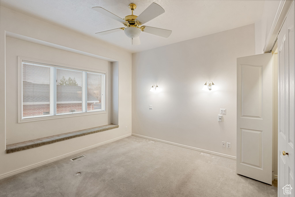 Spare room with a ceiling fan, carpet, baseboards, and visible vents
