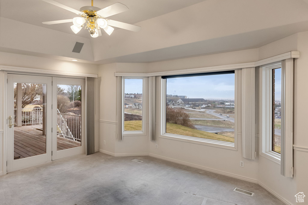 Carpeted empty room featuring lofted ceiling, baseboards, ceiling fan, and visible vents