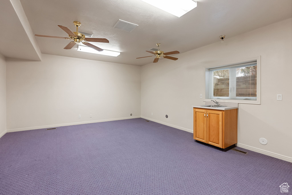 Unfurnished room with dark carpet, ceiling fan, and a sink
