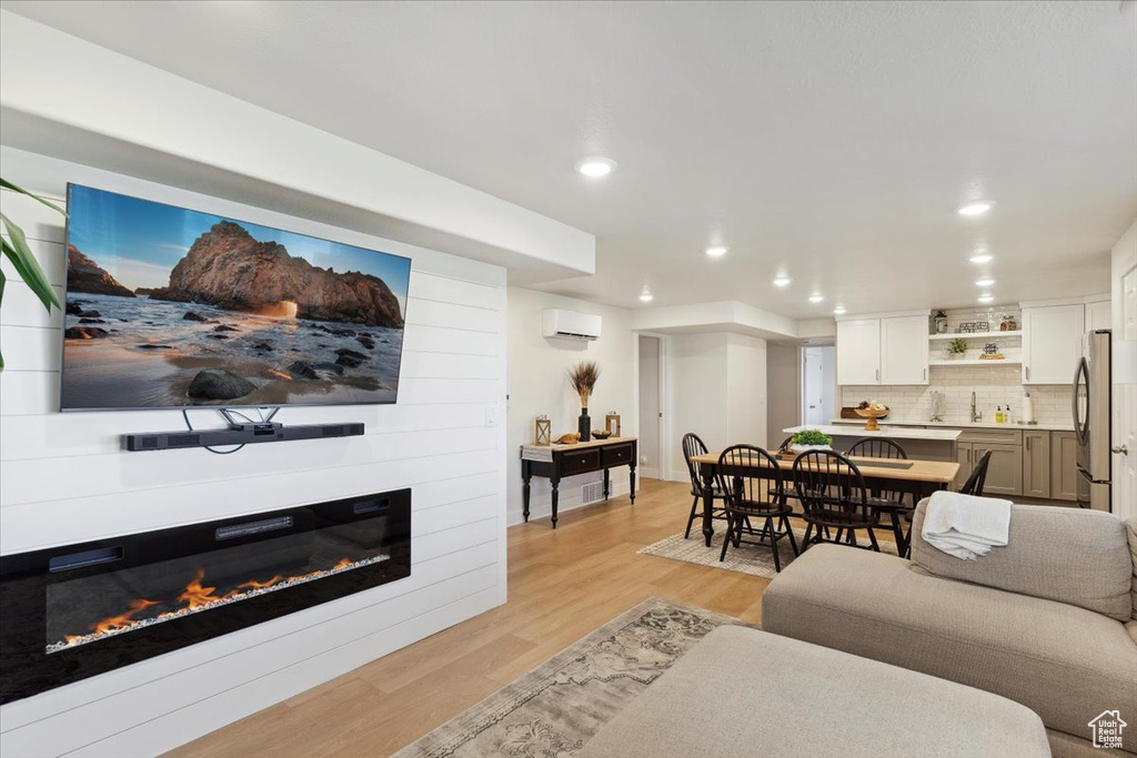 Living room featuring an AC wall unit, recessed lighting, light wood finished floors, and a large fireplace