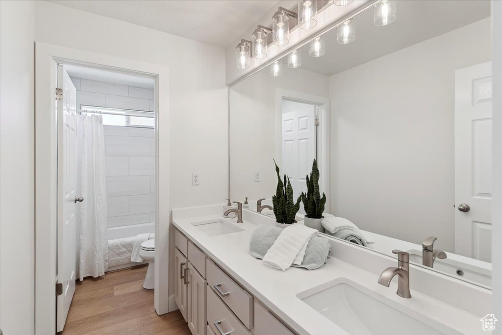 Bathroom with double vanity, toilet, a sink, and wood finished floors