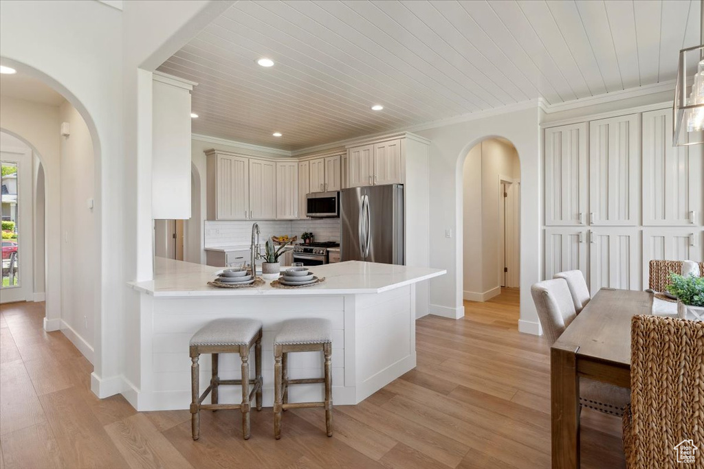 Kitchen with a peninsula, baseboards, light countertops, arched walkways, and appliances with stainless steel finishes