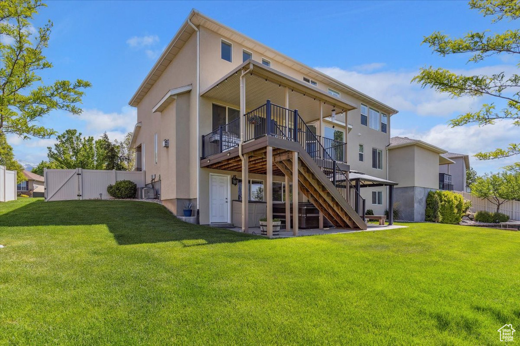Back of house featuring a gate, a wooden deck, stucco siding, and stairway