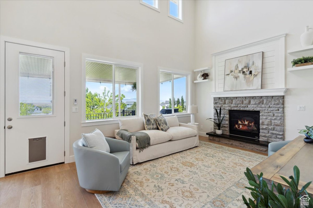 Living area with a high ceiling, a stone fireplace, and wood finished floors