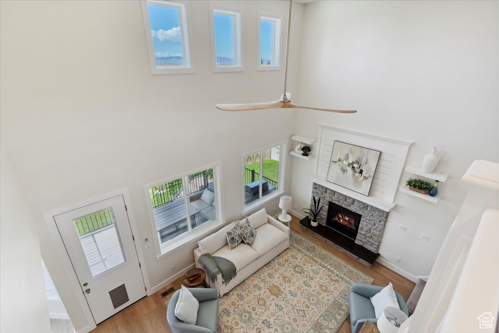 Living room featuring baseboards, a stone fireplace, wood finished floors, and a towering ceiling