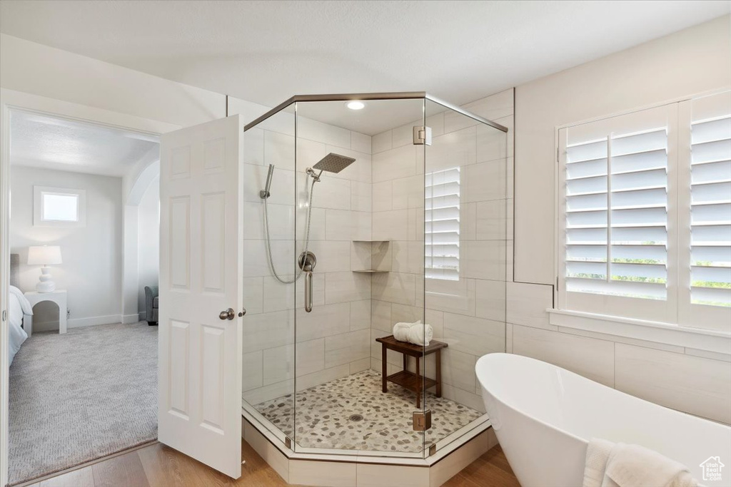 Full bath with a soaking tub, a stall shower, and wood finished floors