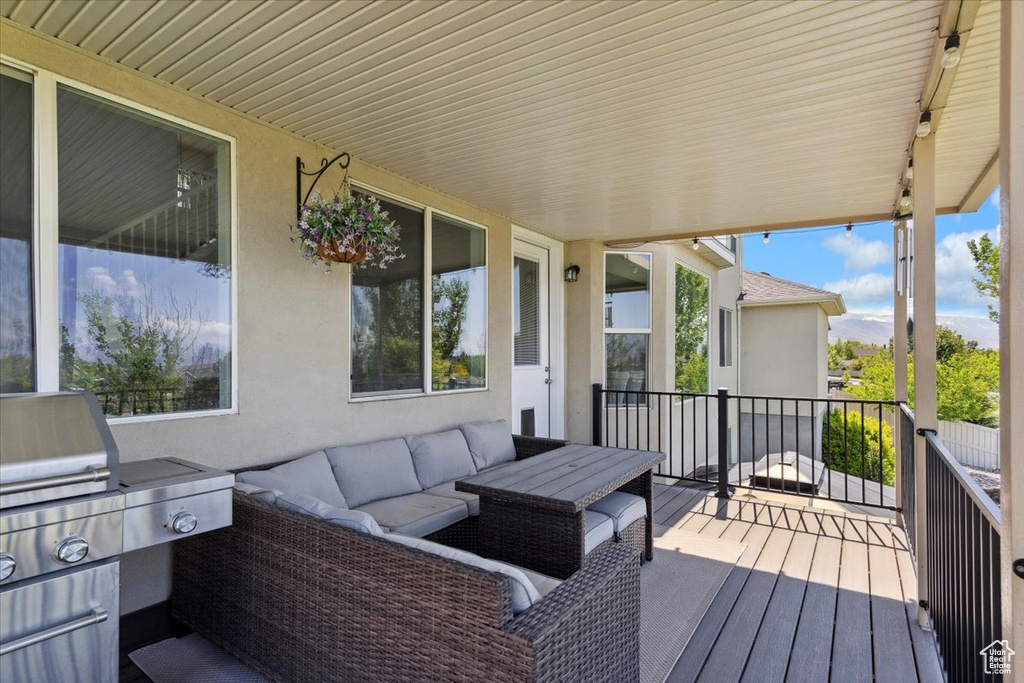 Wooden deck featuring an outdoor hangout area and a grill