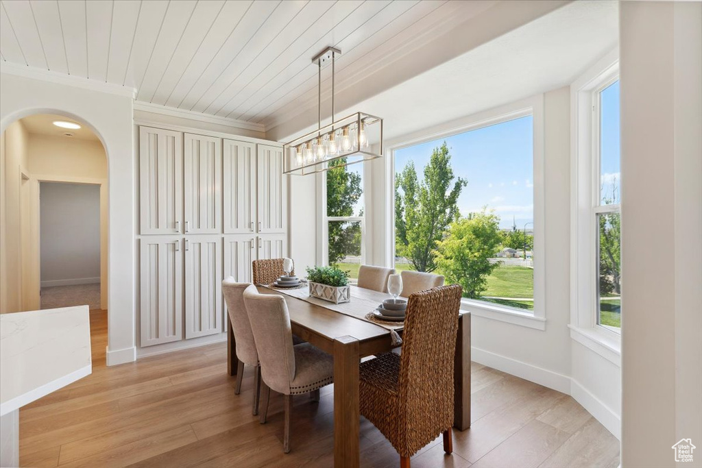 Dining room with ornamental molding, baseboards, wooden ceiling, arched walkways, and a notable chandelier