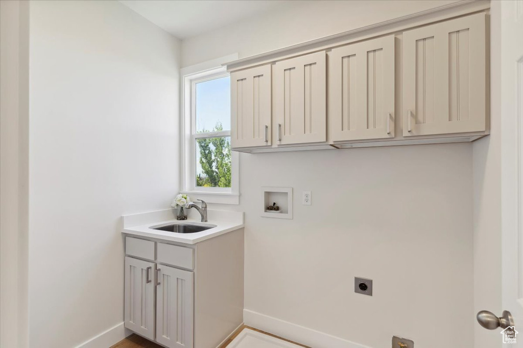 Washroom with washer hookup, electric dryer hookup, cabinet space, a sink, and baseboards