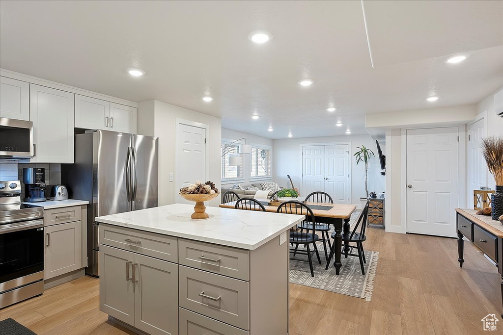 Kitchen with light wood finished floors, appliances with stainless steel finishes, and gray cabinetry