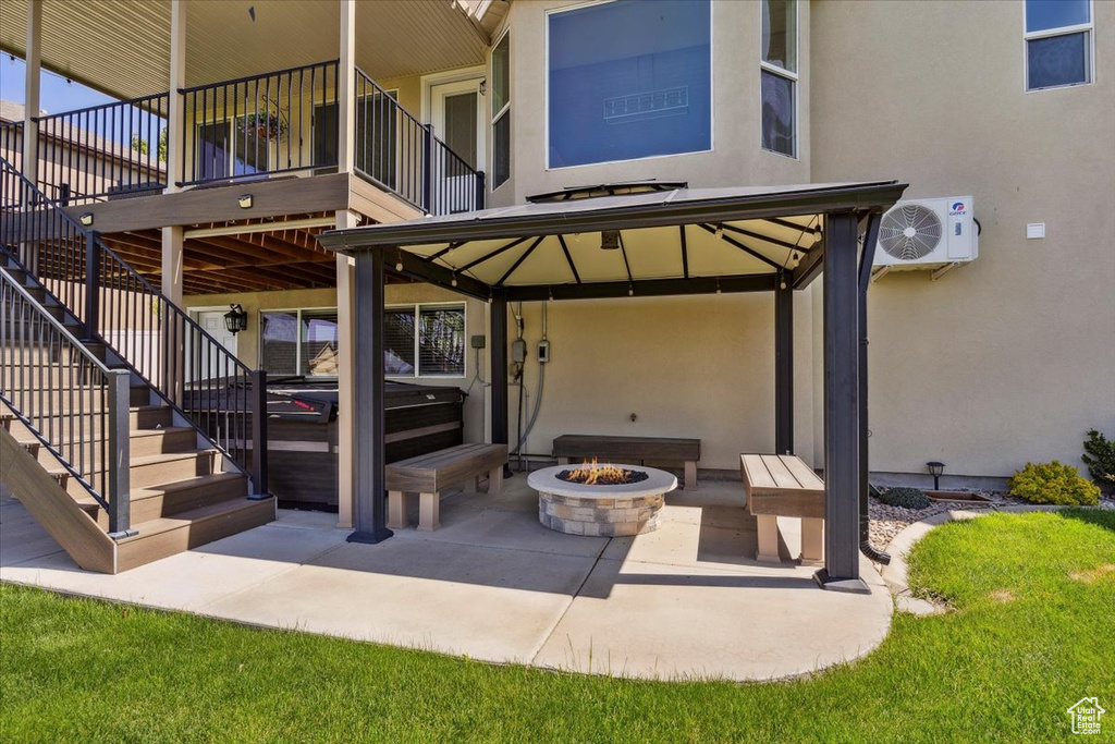 View of patio with ac unit, stairway, a hot tub, a gazebo, and an outdoor fire pit