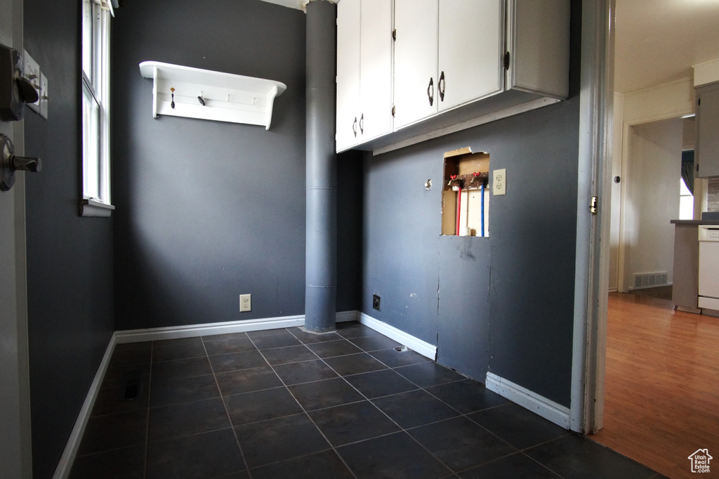 Laundry room featuring dark tile patterned floors, baseboards, and visible vents