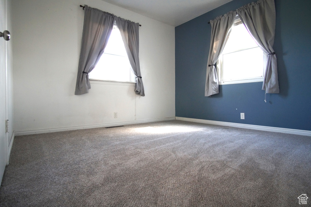 Carpeted empty room with visible vents, baseboards, and a healthy amount of sunlight