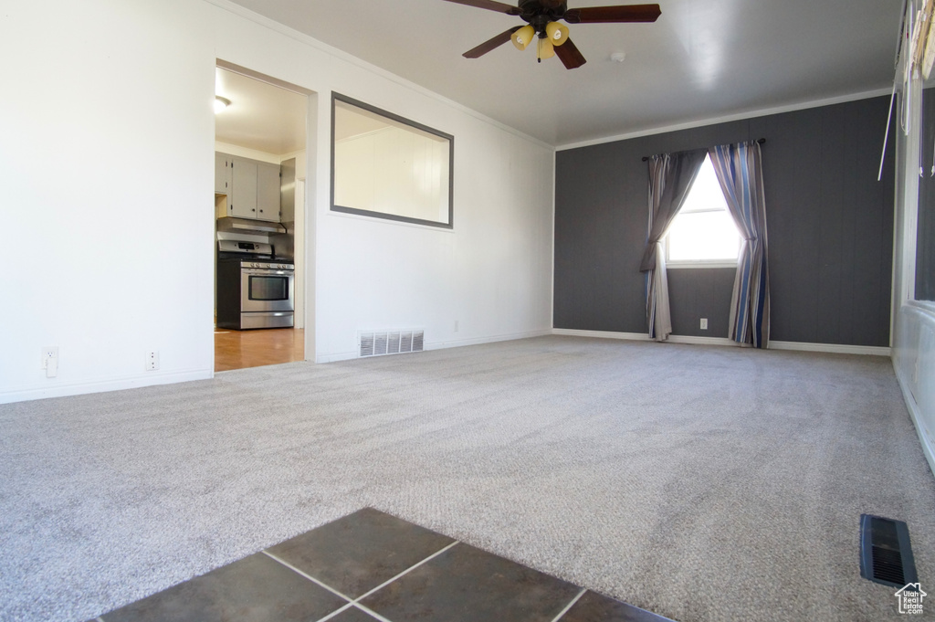 Unfurnished living room with carpet flooring, ceiling fan, ornamental molding, and visible vents